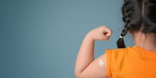 Back view of young child flexing with bandage on upper arm.