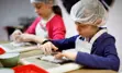 Child wearing apron and hair net, making food from scratch