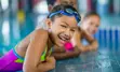 Child in pool wearing bathing suit and goggles