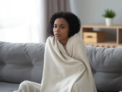 Person wrapped in blanket, looking unwell