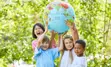 Image of four children outdoors, holding up a globe