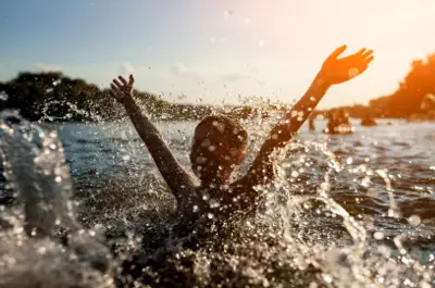 Silhouette of young person making a splash in lake 