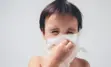 Young child sneezing into a tissue