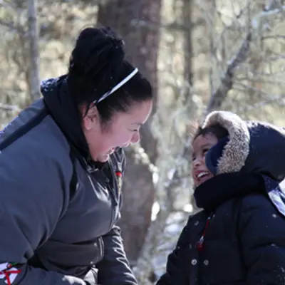 Indigenous child and young adult playing outdoors together in winter