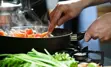 Image of hands cooking food in a pan on stove