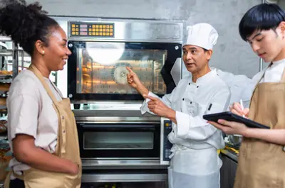 A chef giving a lesson to two others by professional kitchen oven
